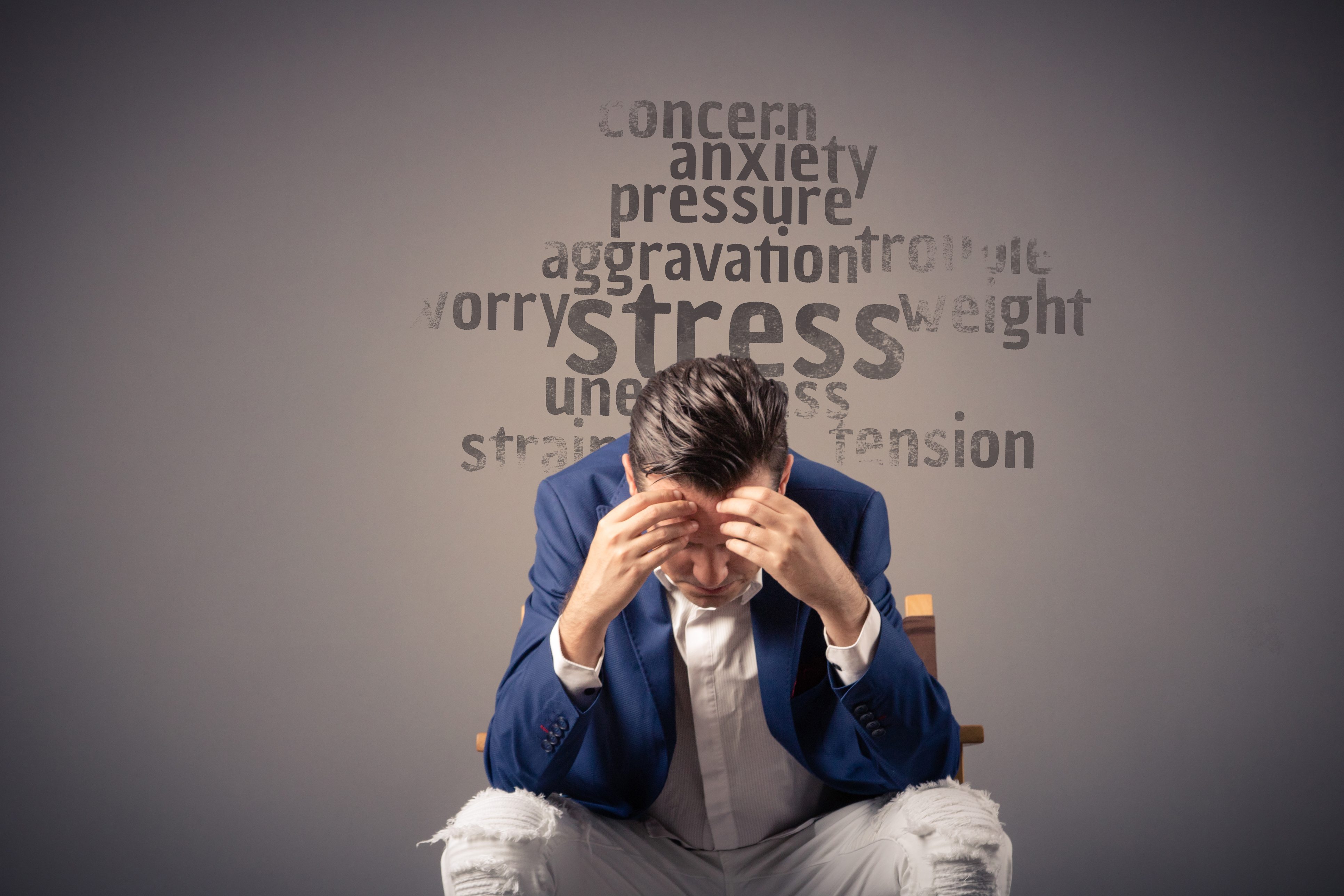 man in suit sitting down with his head in his hands, showing feelings of stress and anxiety