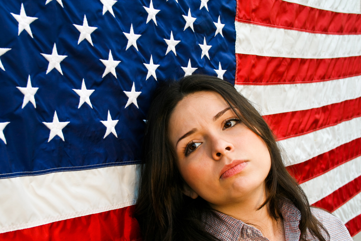 woman in front of the american flag looking sad