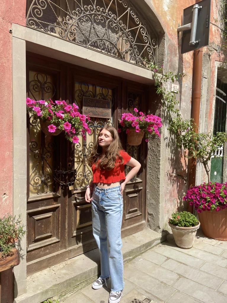 Anahid Mantl in front of a building with flowers.