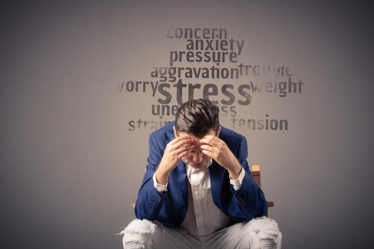 man in suit sitting down with his head in his hands, showing feelings of stress and anxiety