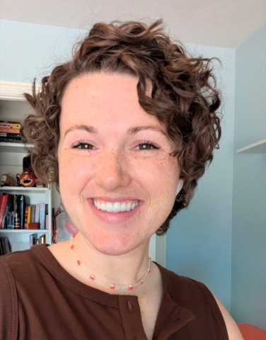 Woman with brown curly hair wearing a brown button up tank top