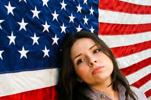 woman in front of the american flag looking sad